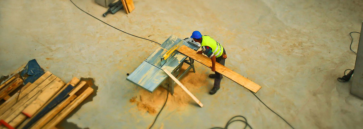 worker operating wood working machine at a construction site